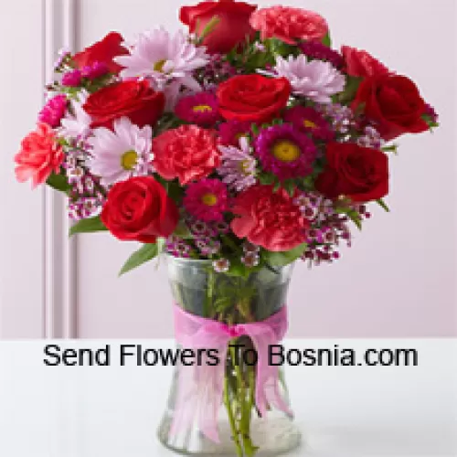 Rosas vermelhas, cravos vermelhos e outras flores sortidas dispostas lindamente em um vaso de vidro
