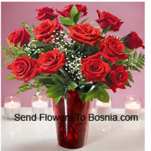 12 rode rozen met wat varens in een glazen vaas